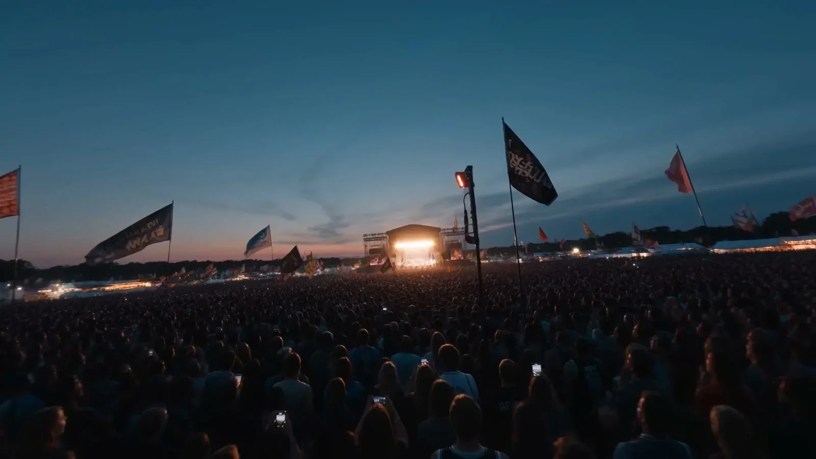 Outdoor music festival crowd with flags at dusk